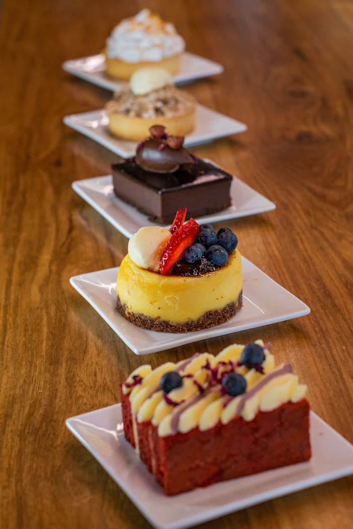 A mouth-watering display of varied desserts arranged on white plates on a wooden table.
